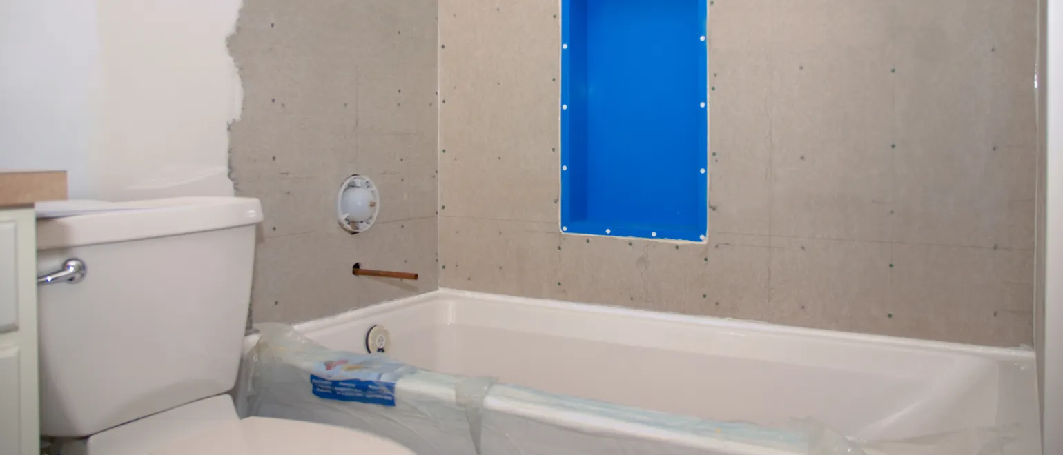 Los Angeles bathroom remodeling project with shower wall tile preparation, bathtub protection, built-in shower niche, and plumbing upgrade work in progress